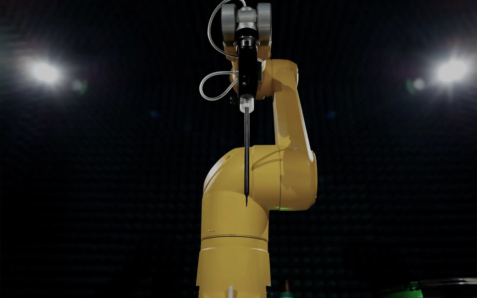 Yellow industrial robot arm under stage lights in the dark